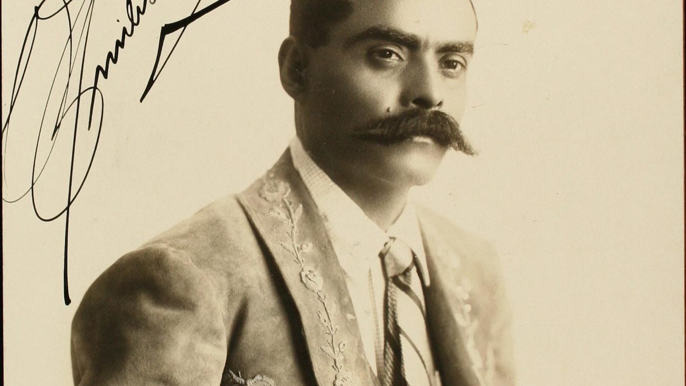 Signed 1915 studio portrait photograph of General Emiliano Zapata in an embroidered jacket, dedicated to General Miguel G. Zamora