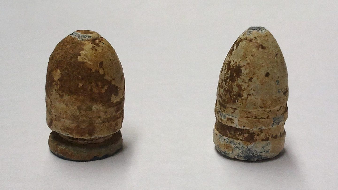 A handful of Civil War-era cylindro-conoidal Minié balls with visible hollow bases, arranged on a plain surface
