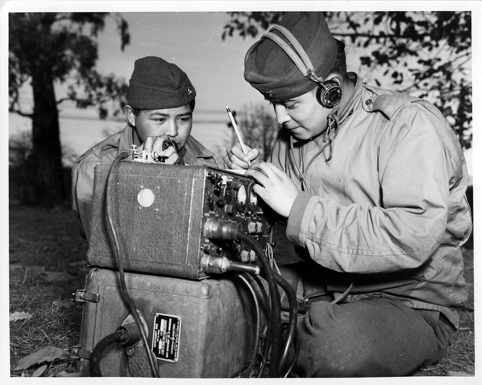 Private First Class Preston Toledo and Private First Class Frank Toledo, Navajo cousins attached to a Marine artillery regiment, relaying orders over a field radio in the South Pacific in July 1943