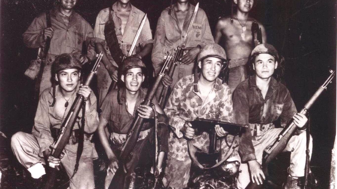 Group photograph of eight Navajo code talkers, Marine Corps radiomen photographed on Bougainville in 1943, posed with rifles and a submachine gun