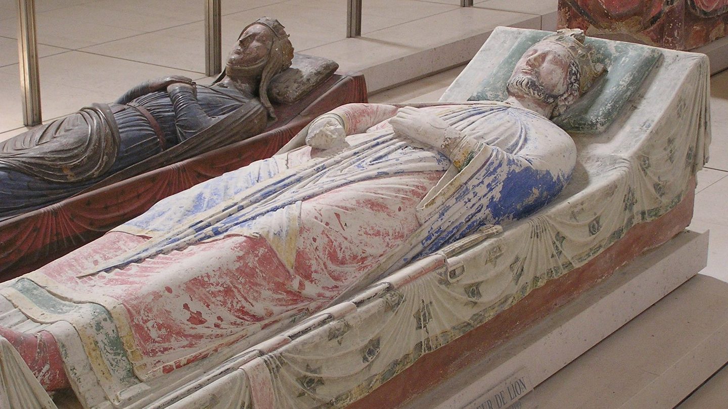 Photograph of Richard the Lionheart's painted stone tomb effigy at Fontevraud Abbey, showing the crowned king lying in repose with another painted effigy visible behind him