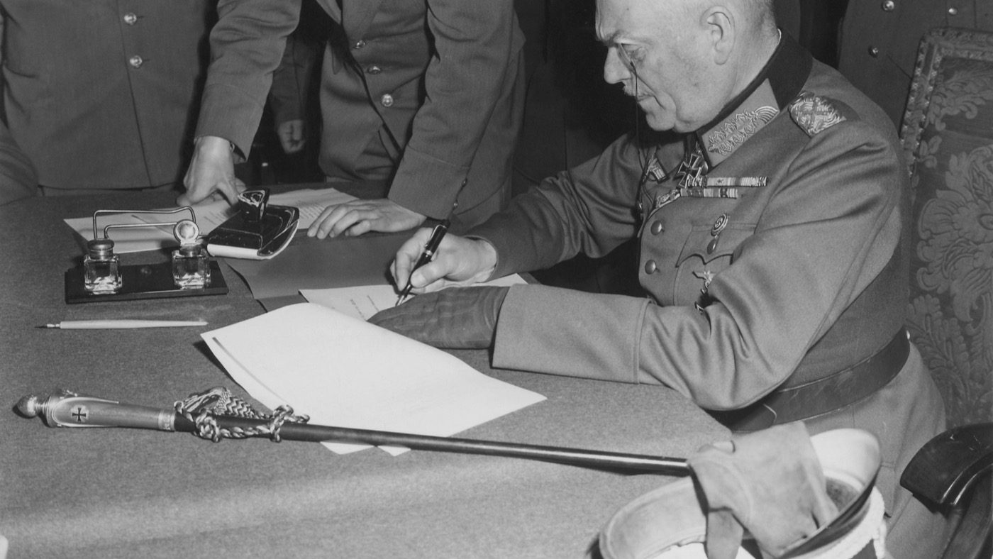 Field Marshal Wilhelm Keitel, seated at a table, signing the German instrument of surrender at Soviet headquarters in Berlin-Karlshorst on May 8, 1945