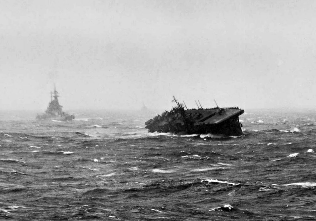 The light aircraft carrier USS Langley rolling heavily in high seas during Typhoon Cobra on December 18, 1944, with a battleship visible steaming behind it